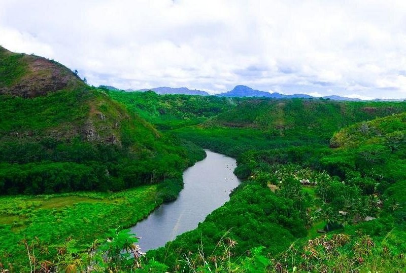 A river winding through a wide green valley below the mountains