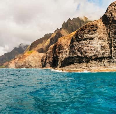 A layered sea cliff dropping straight into clear water